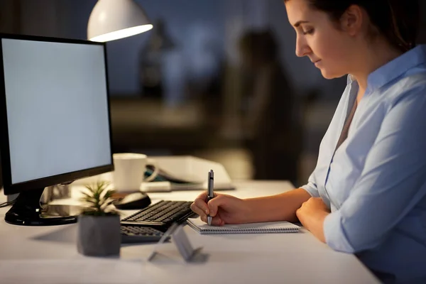 Empresária escrevendo para notebook no escritório da noite — Fotografia de Stock