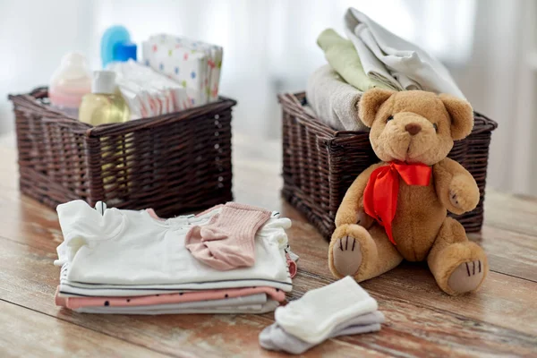 Bebek kıyafetleri ve oyuncak ayılar evdeki masada. — Stok fotoğraf