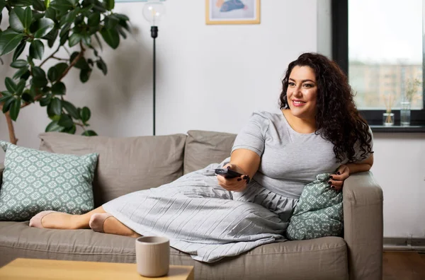 Žena s dálkovým ovládáním a sledování televize doma — Stock fotografie