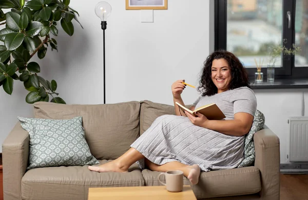 Heureuse jeune femme avec journal intime sur canapé à la maison — Photo