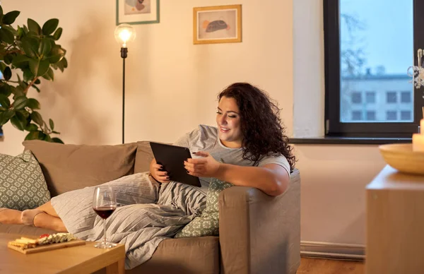 Kvinna med surfplatta, rött vin och snacks hemma — Stockfoto