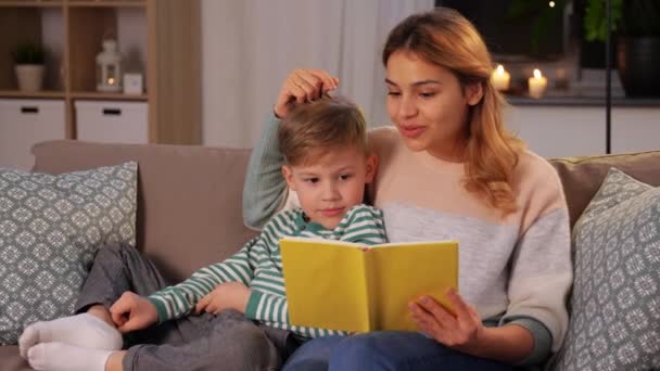 Happy mother and son reading book sofa at home — Stok video