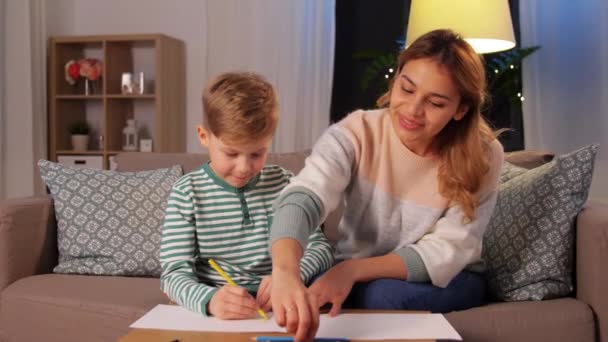 Мать и сын с карандашами рисуют дома — стоковое видео