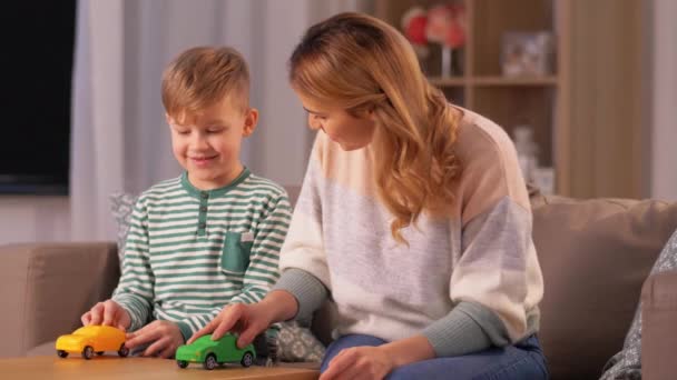 母親と息子はおもちゃの車で家で遊んでいます — ストック動画
