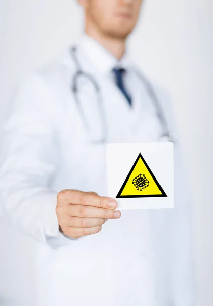 Male doctor holding coronavirus caution sign — Stock Photo, Image