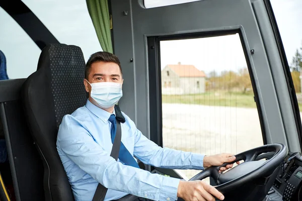 Водитель в медицинской маске за рулем междугороднего автобуса — стоковое фото