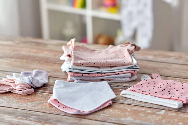 Baby clothes on wooden table at home — Stockfoto