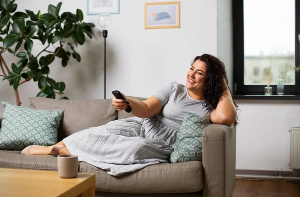 Mulher com controle remoto e assistindo tv em casa — Fotografia de Stock