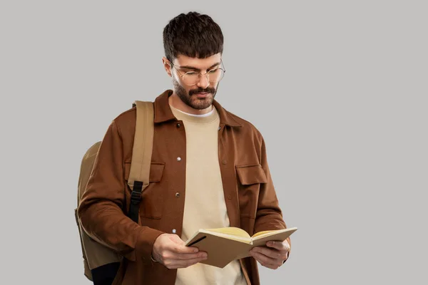 Młody człowiek z plecakiem czytającym pamiętnik — Zdjęcie stockowe