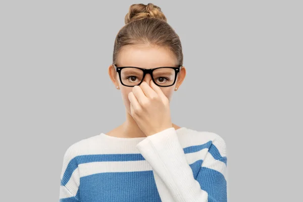 Teenage girl in glasses rubbing nose bridge — Zdjęcie stockowe