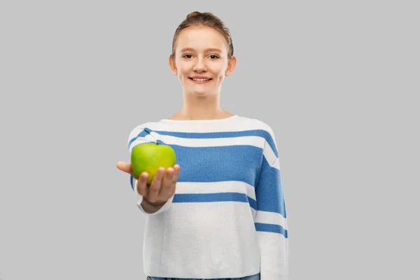 Smiling teenage girl in pullover with green apple — ストック写真