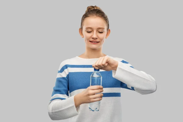 Smiling teenage girl opening bottle of water Stock Kép