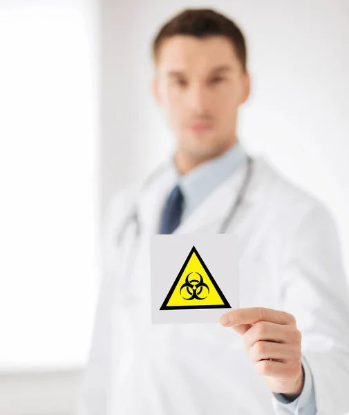 Male doctor holding boihazard caution sign — Stock Photo, Image
