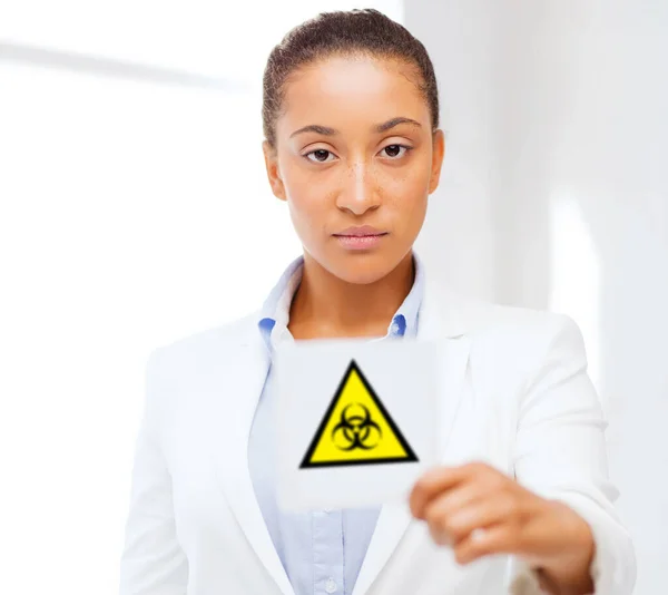 Female doctor holding boihazard caution sign — Stock Photo, Image
