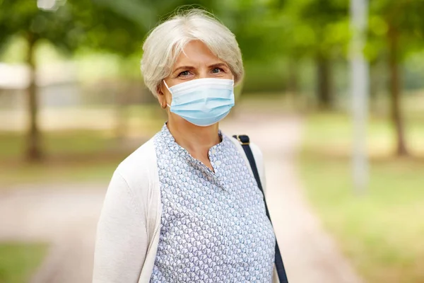 Idős nő védő orvosi maszk a parkban — Stock Fotó