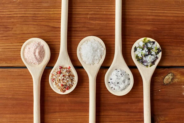 Sendok dengan garam dan rempah-rempah di atas meja kayu — Stok Foto