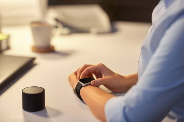 Wanita dengan jam tangan pintar dan speaker di kantor malam — Stok Foto