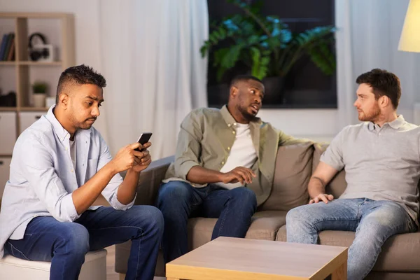 Hombre usando smartphone mientras sus amigos hablan en casa — Foto de Stock