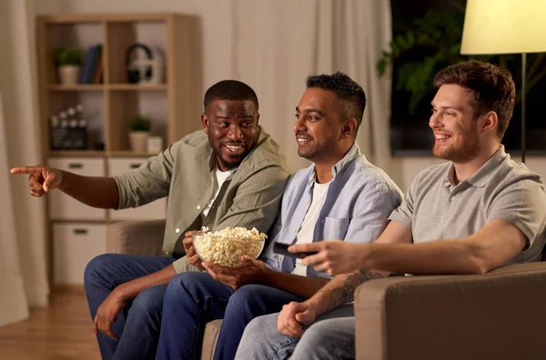 Чоловічі друзі з попкорном дивитися телевізор вдома — стокове фото