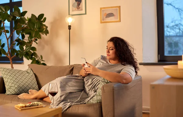 Femme avec smartphone à la maison le soir — Photo