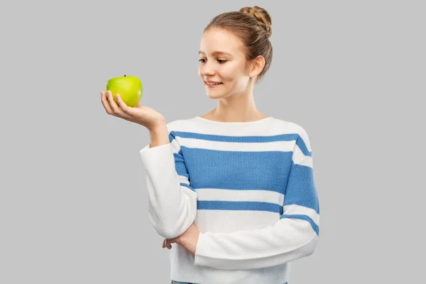 Smiling teenage girl in pullover with green apple — ストック写真