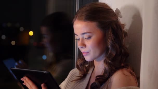 Mladá žena s tabletou PC sedí u okna — Stock video