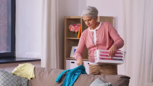 Senior kvinna plocka kläder för tvätt hemma — Stockvideo