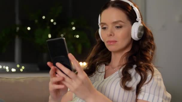Terhes nő okostelefonnal és fülhallgatóval — Stock videók