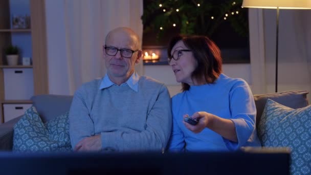 Пожилая пара смотрит телевизор дома вечером — стоковое видео