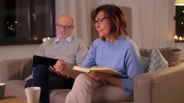 Starší pár s knihou a tabletem PC doma — Stock video