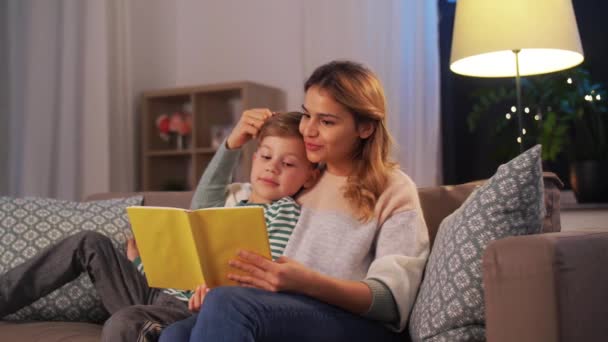 Happy mother and son reading book sofa at home — Stockvideo