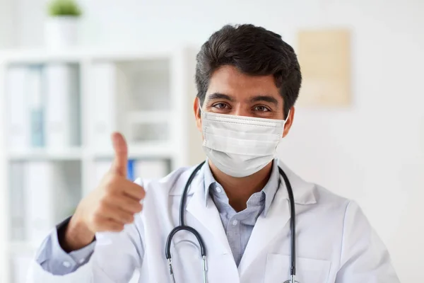 클리닉에서 의료용 마스크를 쓰고 있는 의사가 엄지손가락을 들고 있다 — 스톡 사진