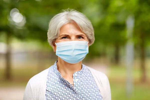 Senior kvinna i skyddande medicinsk mask i parken — Stockfoto