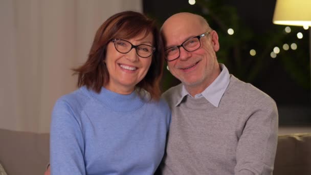 Щаслива старша пара обіймає диван вдома — стокове відео