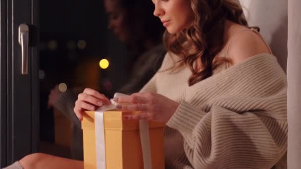 Mujer abriendo regalo de Navidad en casa por la noche — Vídeos de Stock