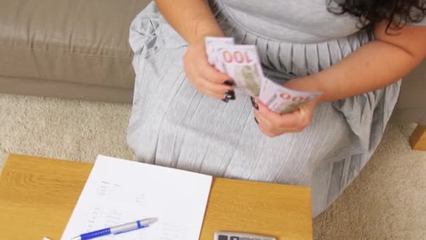 Mujer con dinero, papeles y calculadora en casa — Vídeo de stock