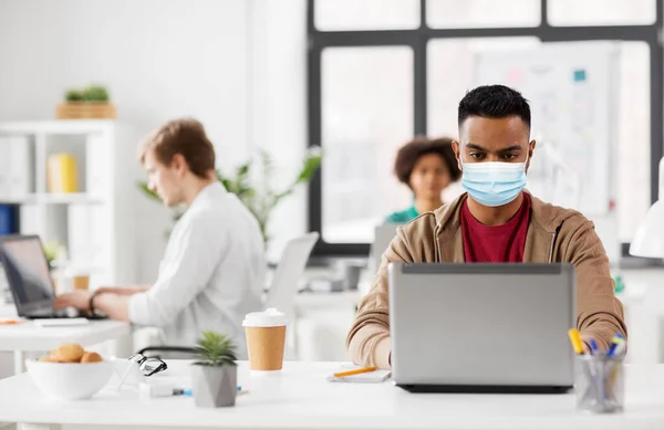 Indian man with laptop in medical mask at office — Stock Photo, Image