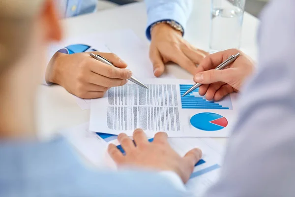 Equipo de negocios manos con bolígrafos y gráficos en la oficina —  Fotos de Stock