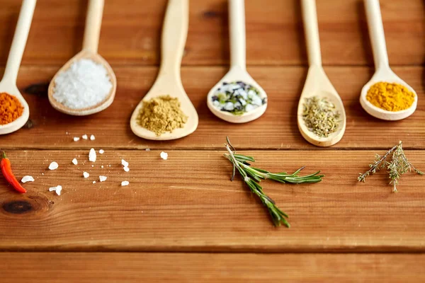 Skedar med kryddor och salt på träbord — Stockfoto