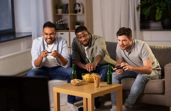 Amigos felices jugando videojuegos en casa por la noche — Foto de Stock