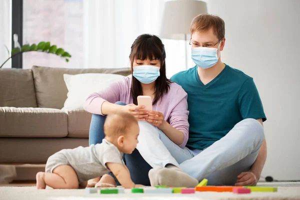 family with baby in medical masks at home