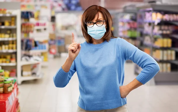 Boze oudere vrouw met medisch masker in de supermarkt — Stockfoto