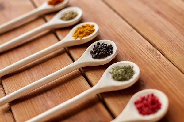Spoons with different spices on wooden table — Stock Photo, Image