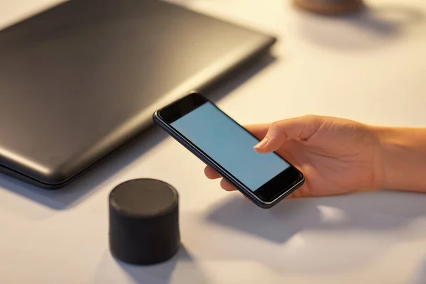 stock image hand with smartphone and smart speaker at office