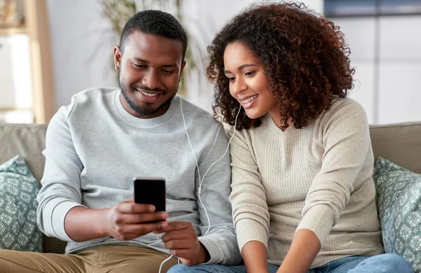 Glückliches Paar mit Smartphone und Kopfhörer zu Hause — Stockfoto