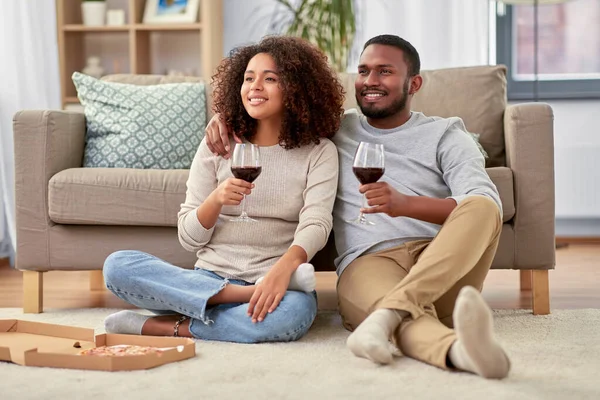 Счастливая пара с вином и пиццей на вынос дома — стоковое фото
