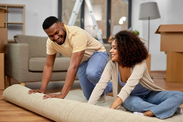 Glückliches Paar mit Teppich zieht in neues Zuhause — Stockfoto