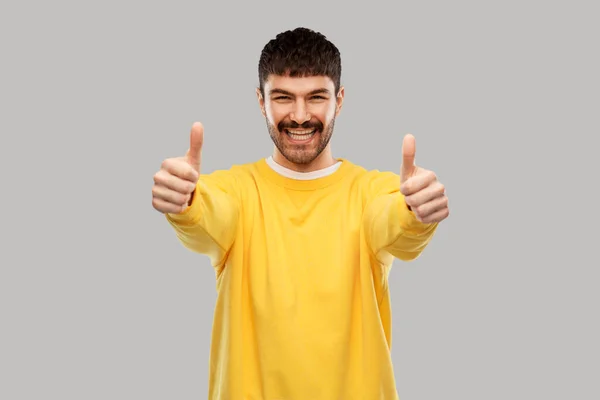 Sonriente joven mostrando los pulgares hacia arriba —  Fotos de Stock