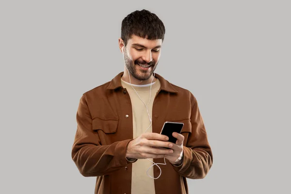 Leende ung man med hörlurar och smartphone — Stockfoto