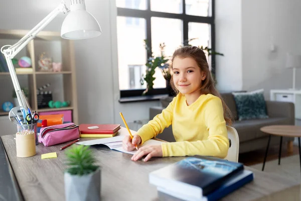 Student flicka med bok skriva till anteckningsbok hemma — Stockfoto